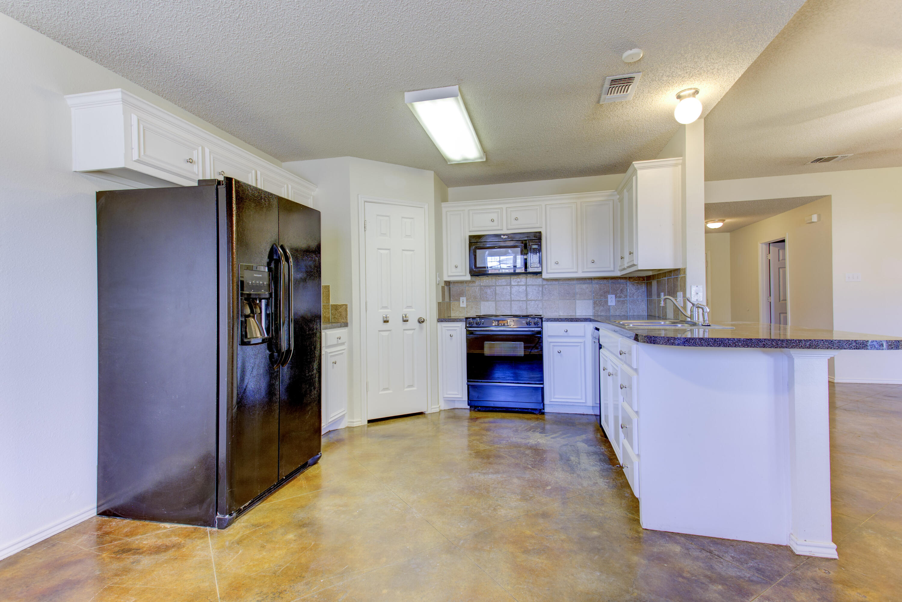 6804 7th Street Lubbock, TX 79416 - Photo 26 of 42 a large kitchen with a refrigerator and a stove