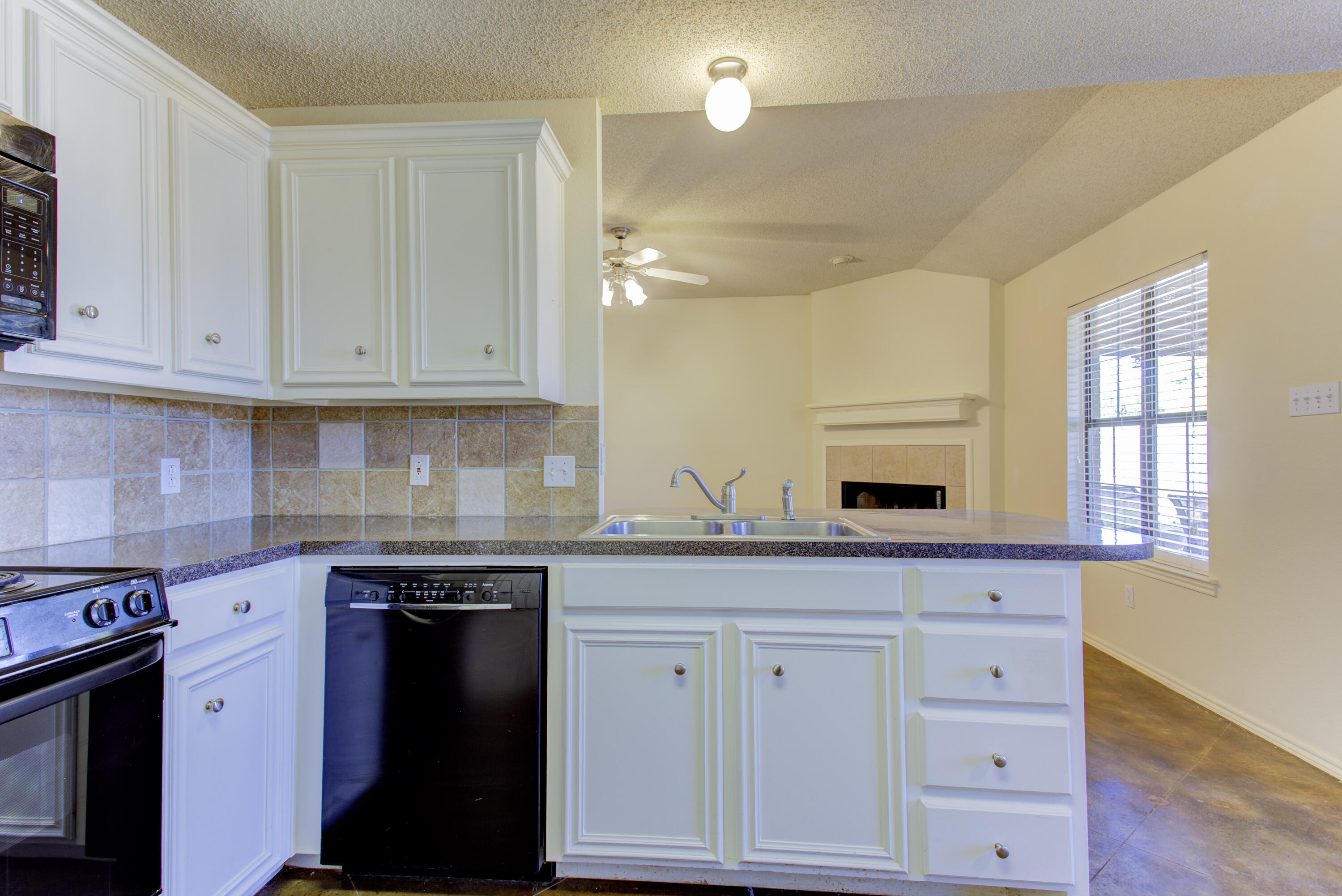 6804 7th Street Lubbock, TX 79416 - Photo 27 of 42 a kitchen with granite countertop white cabinets and black appliances