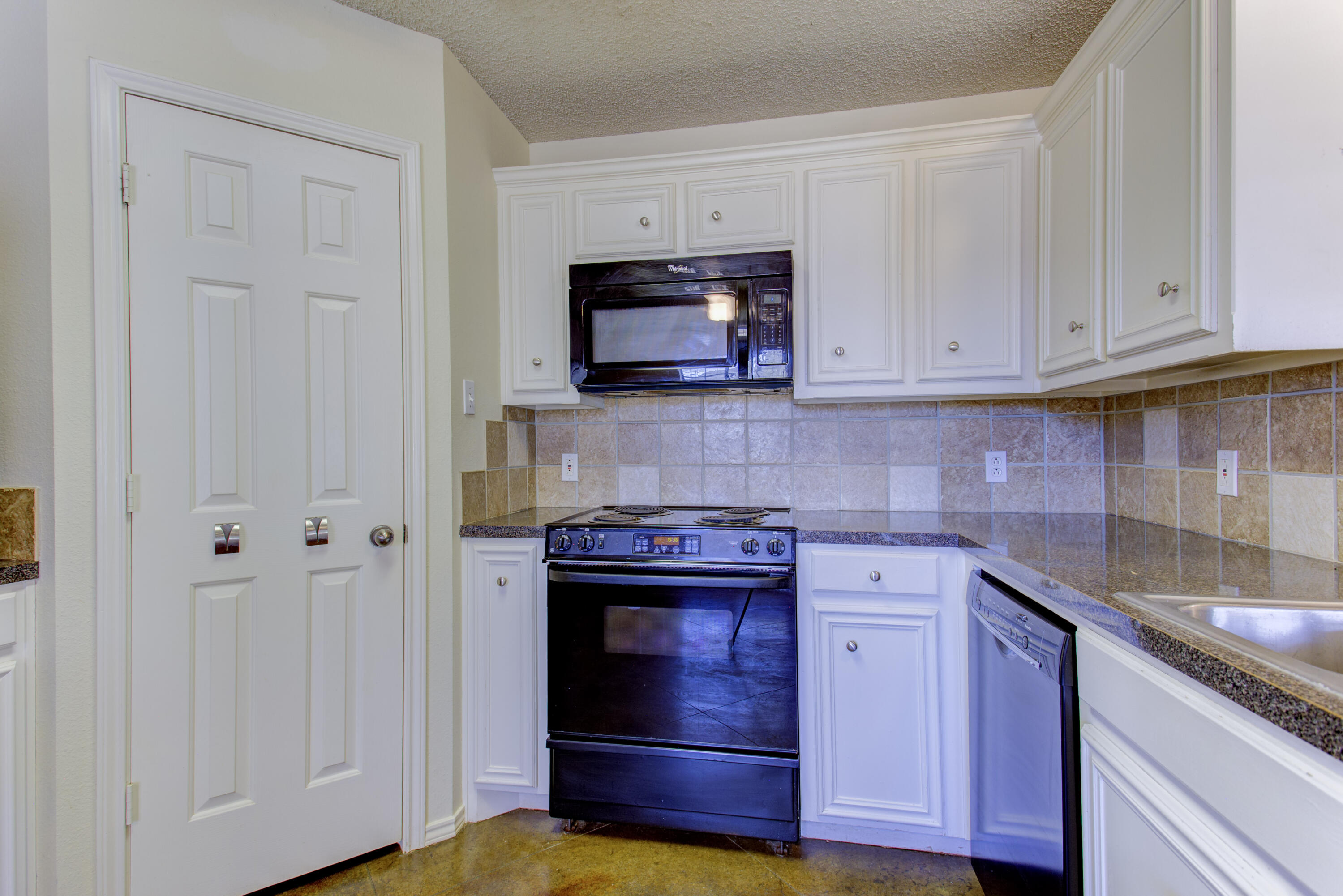 6804 7th Street Lubbock, TX 79416 - Photo 28 of 42 a kitchen with stainless steel appliances granite countertop white cabinets and a stove top oven