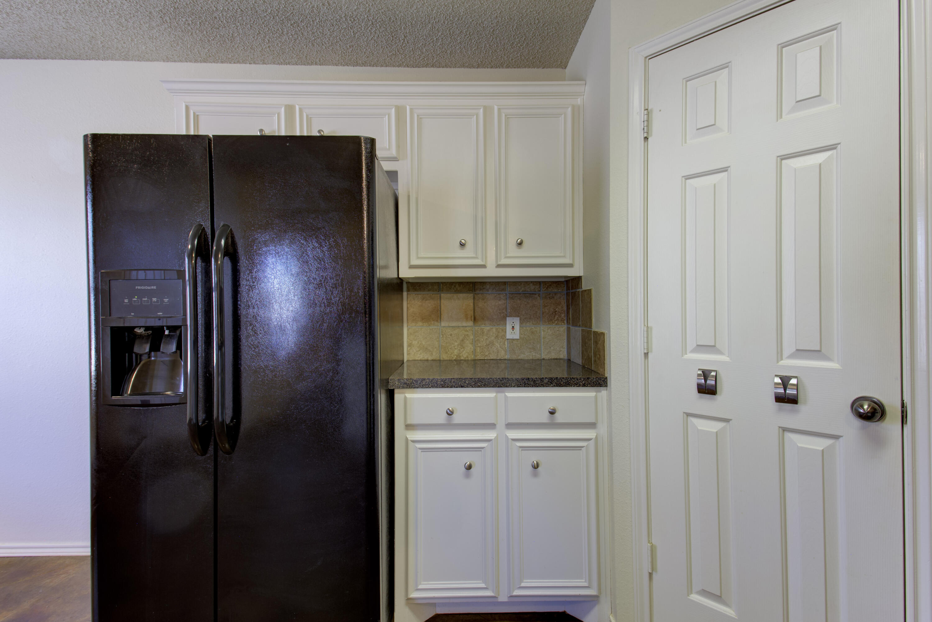 6804 7th Street Lubbock, TX 79416 - Photo 30 of 42 a kitchen with white cabinets and refrigerator