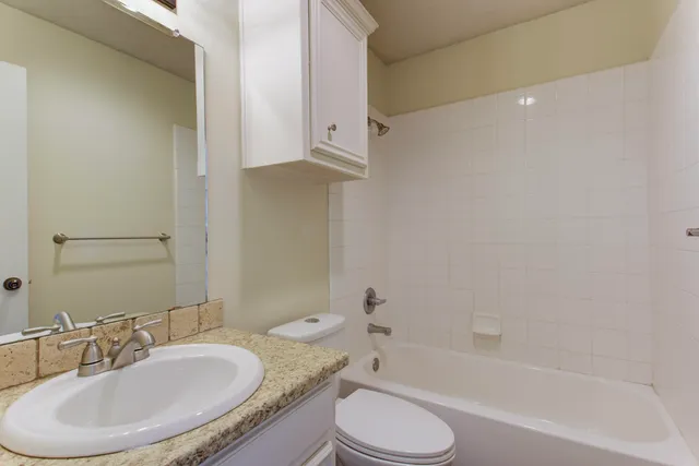 a bathroom with a granite countertop sink a mirror and a bath tub