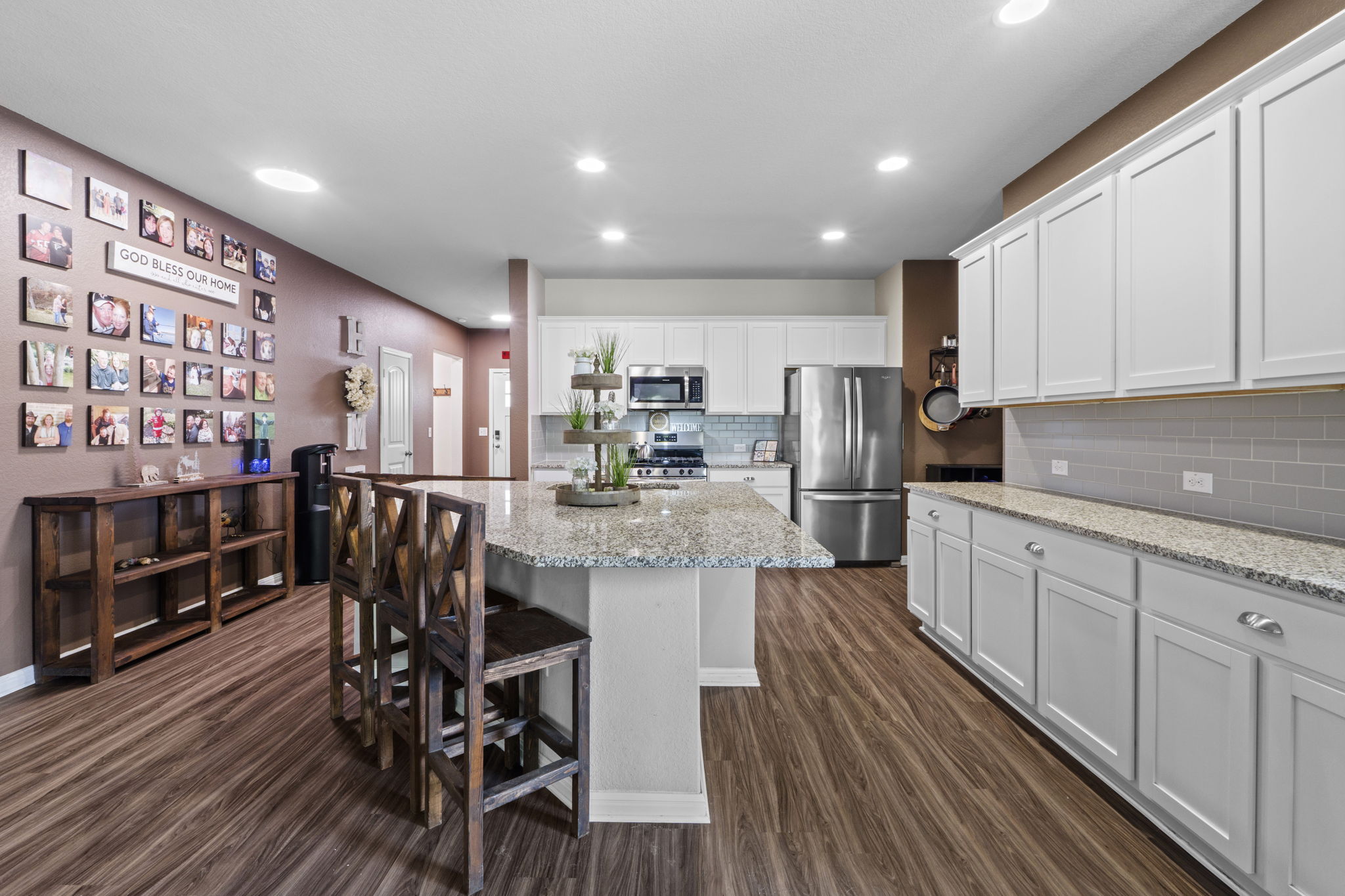 2417 Bridges Ranch Road Georgetown, TX 78628 - Photo 21 of 36 Kitchen with stainless steel appliances, white cabinets, light stone countertops, dark wood finished floors, and a breakfast bar