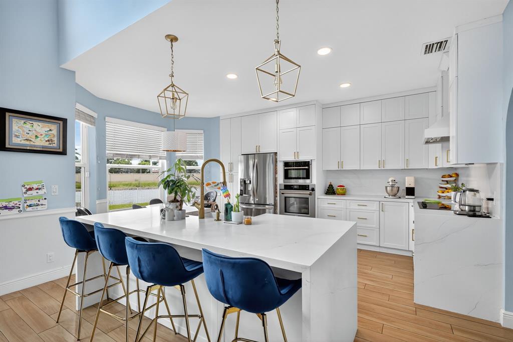 18676 Southwest 16th Street Pembroke Pines, FL 33029 - Photo 15 of 61 a kitchen with stainless steel appliances kitchen island granite countertop a dining table chairs and white cabinets