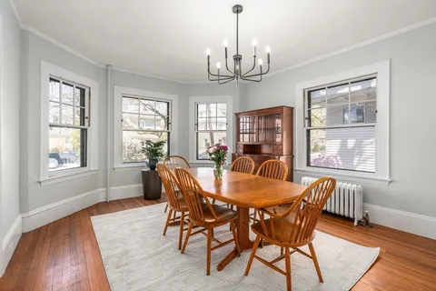 a view of a dining room with furniture a chandelier and wooden floor