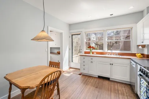 a open kitchen with stainless steel appliances granite countertop a dishwasher a stove a dining table and chairs with wooden floor