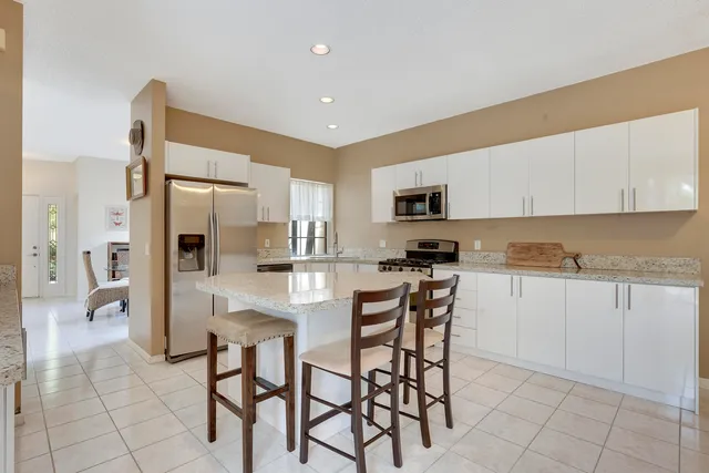 a kitchen with stainless steel appliances kitchen island granite countertop a refrigerator and cabinets
