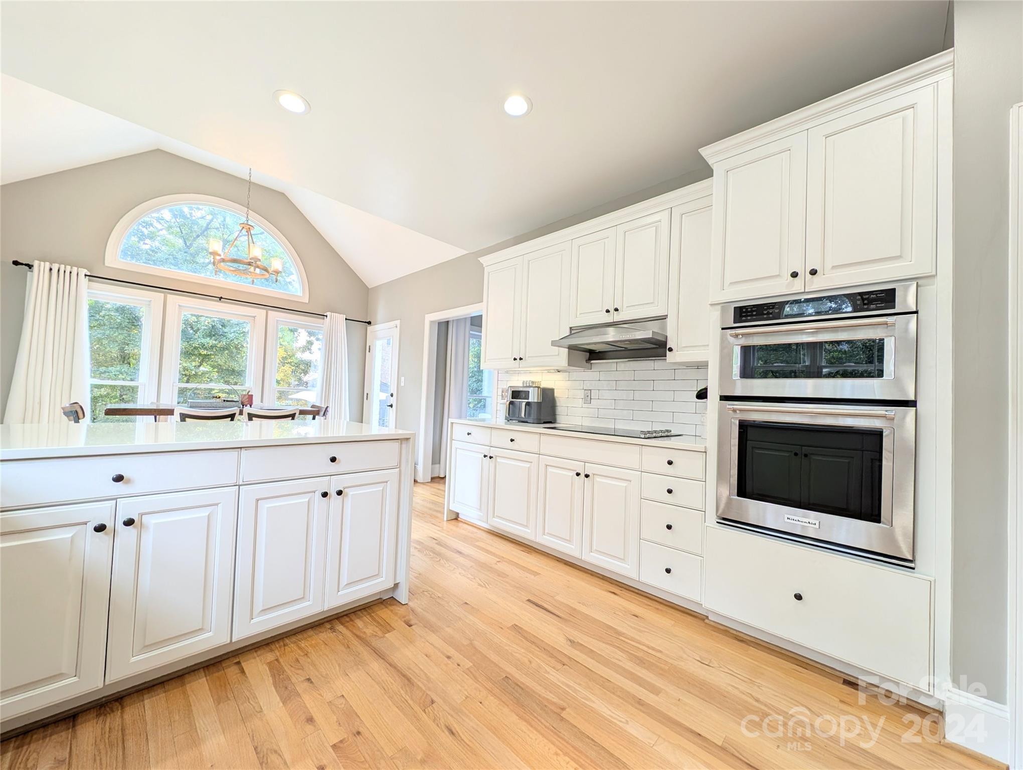 640 Amberly Crossing Fort Mill, SC 29708 - Photo 9 of 45 a large white kitchen with granite countertop a stove a sink a window and white cabinets