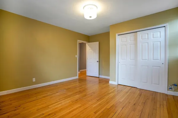 an empty room with wooden floor and fan