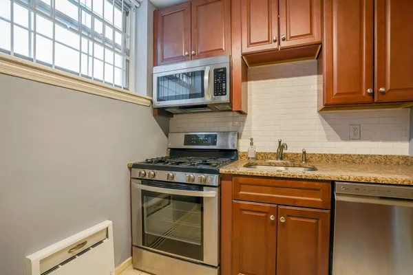 a kitchen with granite countertop a stove top oven cabinetry a sink and a window
