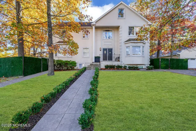 a front view of a house with a yard and trees