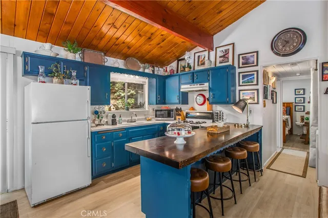 a kitchen with stainless steel appliances granite countertop a refrigerator a sink dishwasher a stove and a dining table with wooden floor