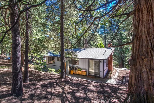 a view of a house with large trees and wooden fence