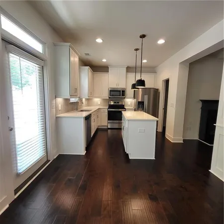 a living room with stainless steel appliances granite countertop furniture wooden floor and a view of kitchen