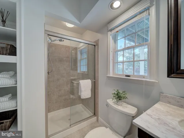 a bathroom with a granite countertop bathtub shower sink mirror and toilet