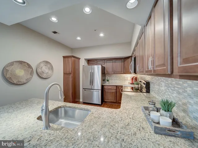 a kitchen with stainless steel appliances granite countertop a sink a stove and a refrigerator