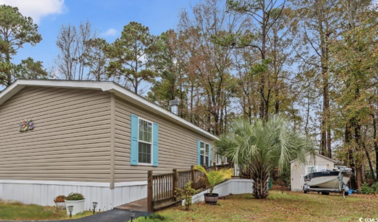 View of side of home with a deck and a lawn