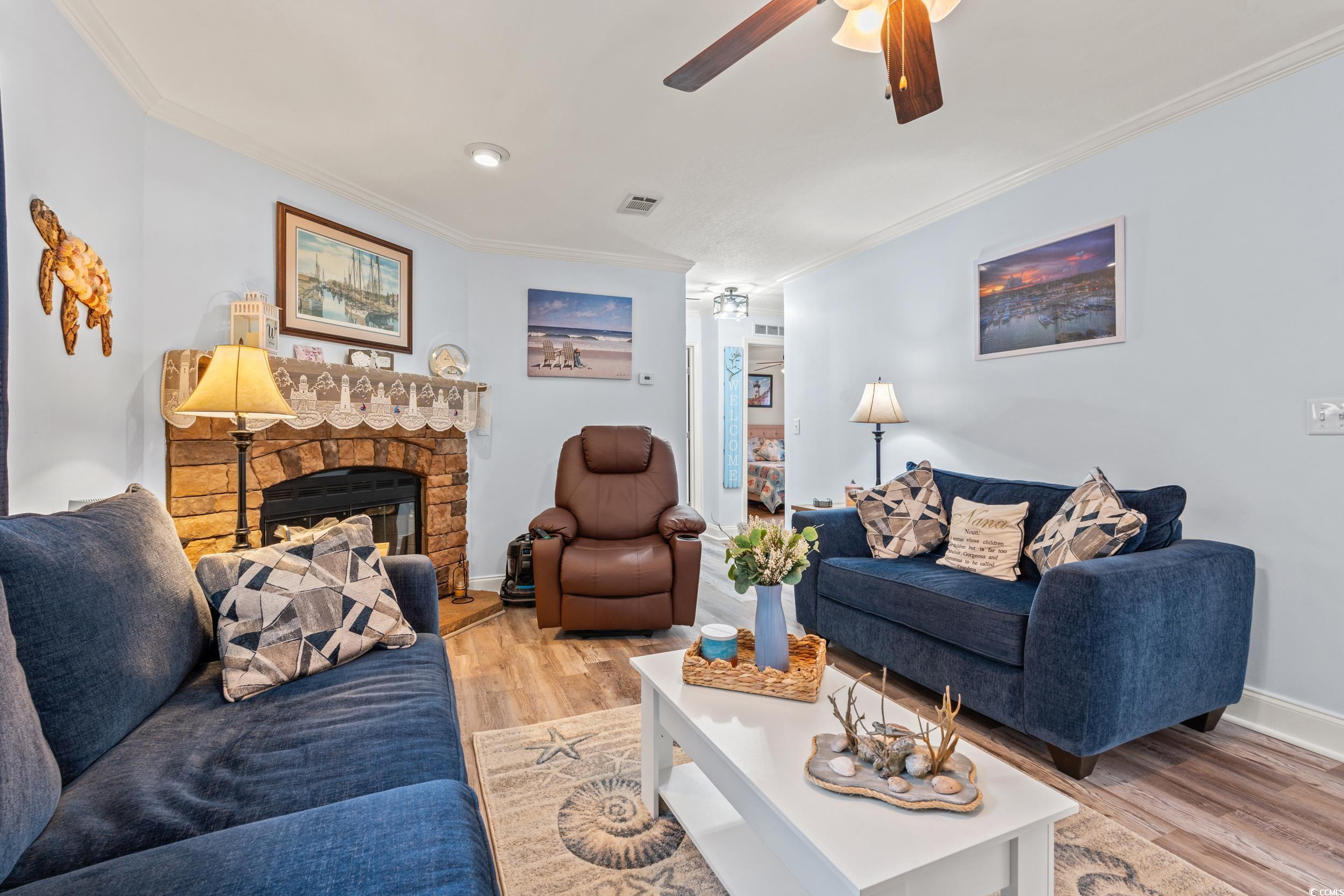 90 Offshore Drive Murrells Inlet, SC 29576 - Photo 8 of 40 Living area with a stone fireplace, a ceiling fan, light wood-style flooring, and crown molding