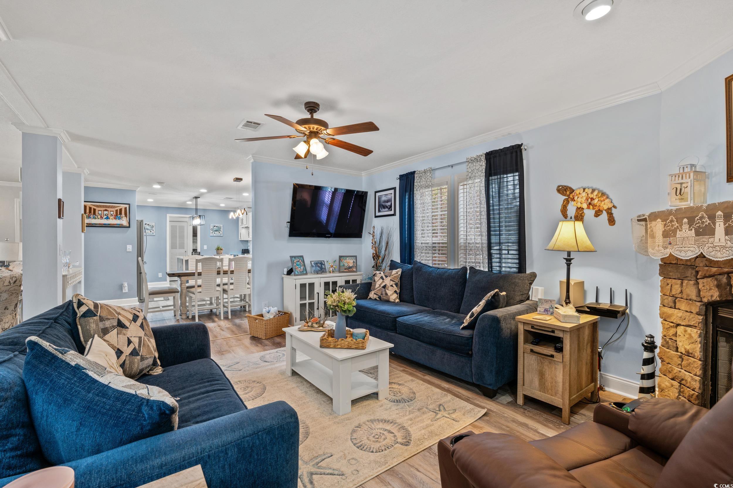 90 Offshore Drive Murrells Inlet, SC 29576 - Photo 9 of 40 Living area featuring a stone fireplace, wood finished floors, crown molding, ceiling fan, and recessed lighting