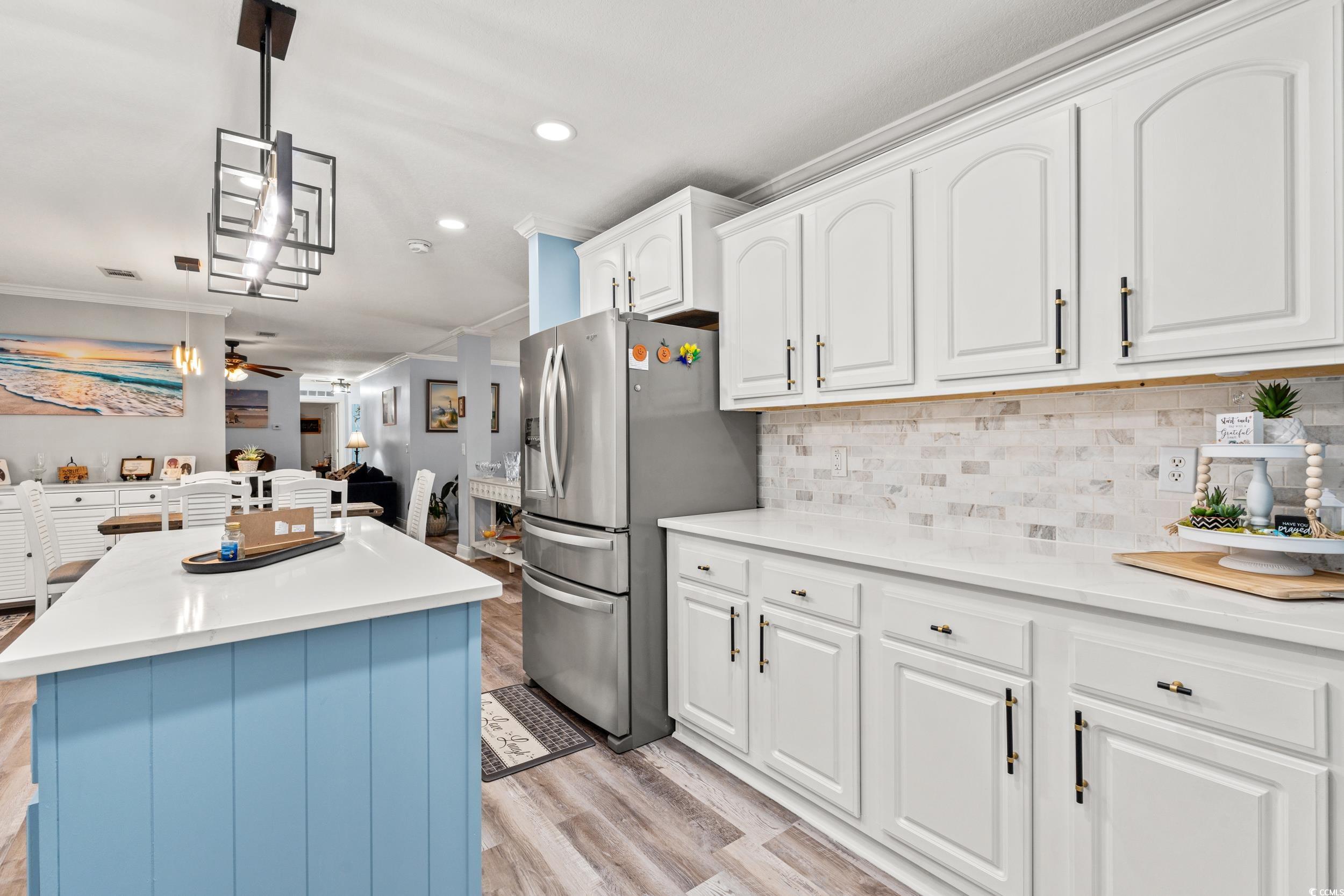 90 Offshore Drive Murrells Inlet, SC 29576 - Photo 40 of 40 Kitchen featuring white cabinets, hanging light fixtures, crown molding, open floor plan, and light wood-type flooring