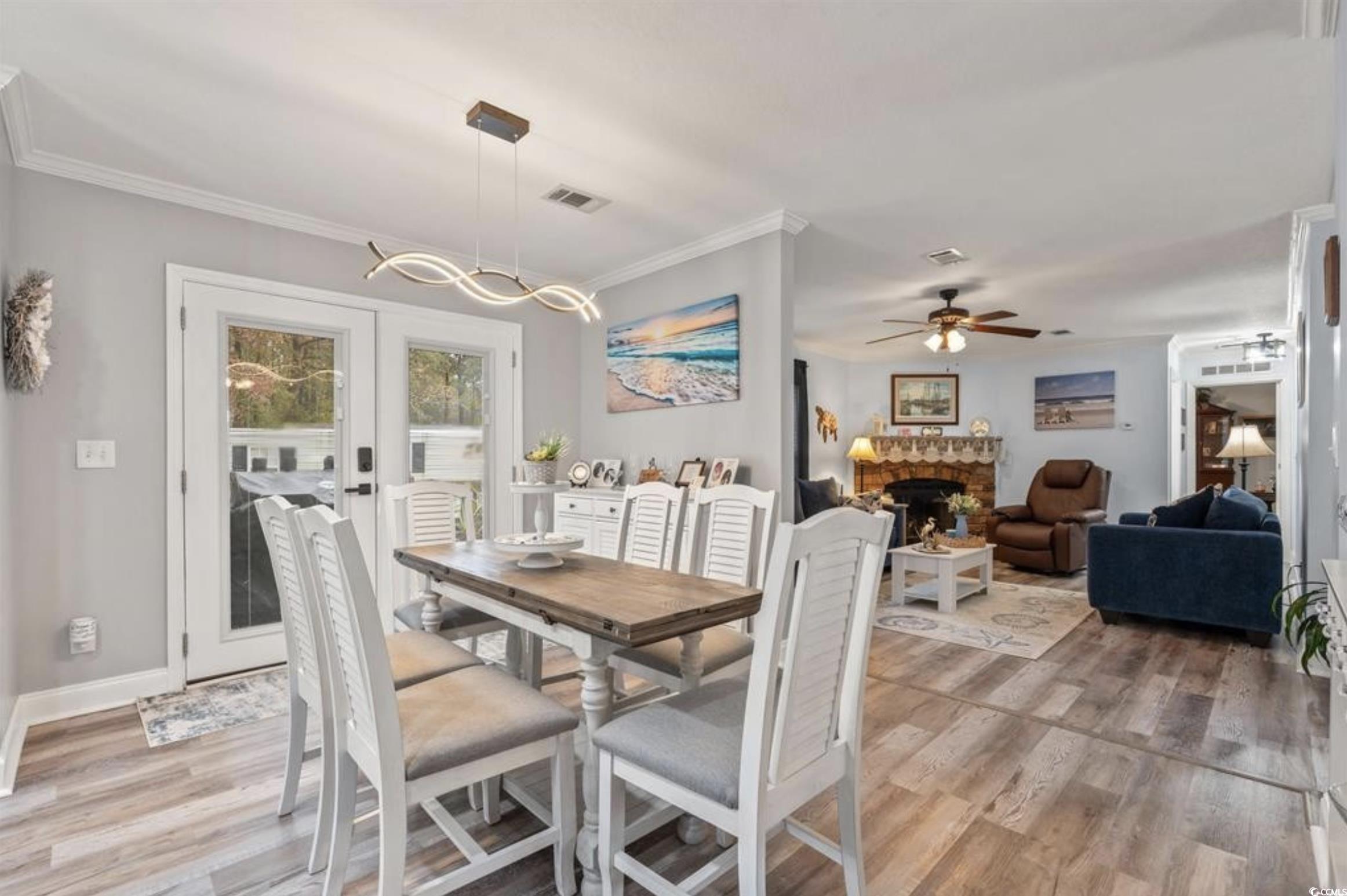 90 Offshore Drive Murrells Inlet, SC 29576 - Photo 6 of 40 Dining area featuring a fireplace, light wood-style flooring, french doors, ceiling fan, and ornamental molding