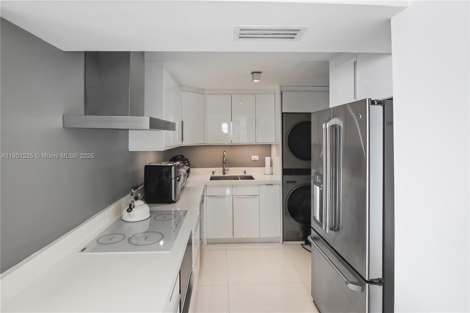 6039 Collins Avenue, Unit 1402 Miami Beach, FL 33140 - Photo 19 of 45 a kitchen with a refrigerator sink and wooden cabinets