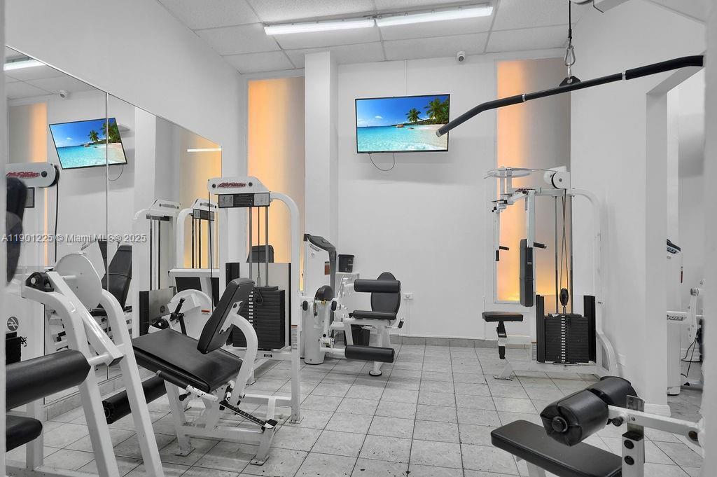 6039 Collins Avenue, Unit 1402 Miami Beach, FL 33140 - Photo 41 of 45 a room with gym equipment and large mirror