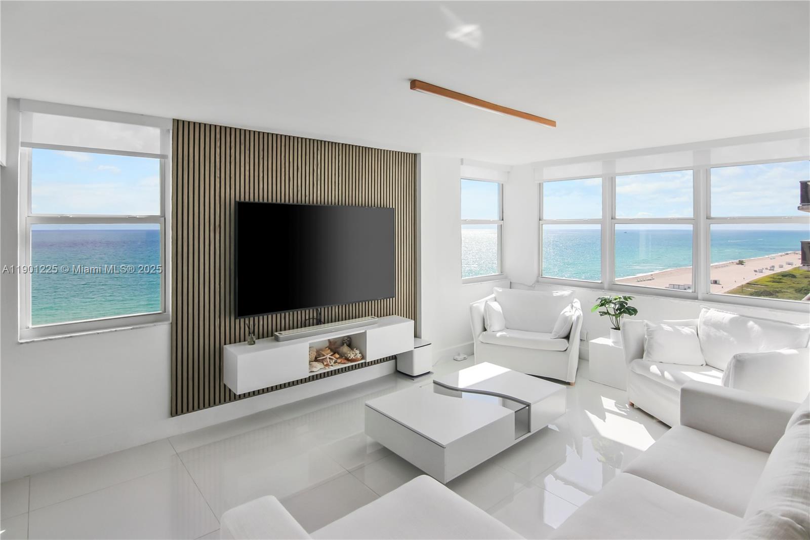 6039 Collins Avenue, Unit 1402 Miami Beach, FL 33140 - Photo 6 of 45 a living room with furniture a flat screen tv and a floor to ceiling window