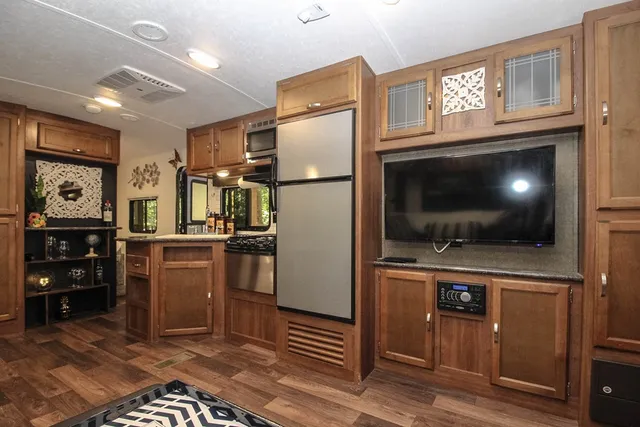 a living room with stainless steel appliances furniture a flat screen tv and a refrigerator