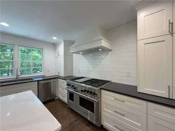 a kitchen with granite countertop a sink stove and cabinets