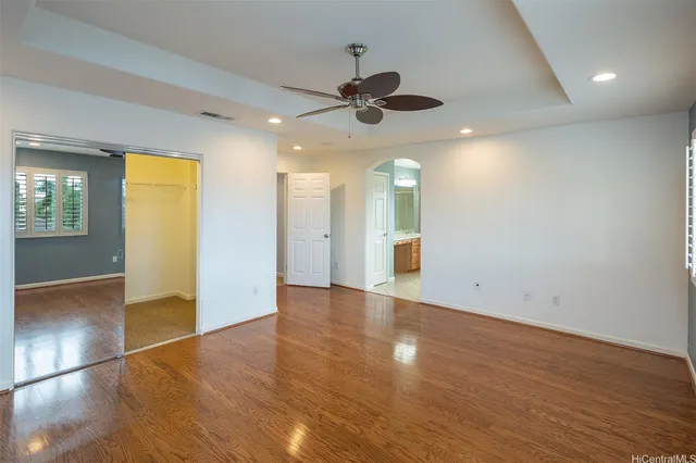 an empty room with wooden floor and a ceiling fan