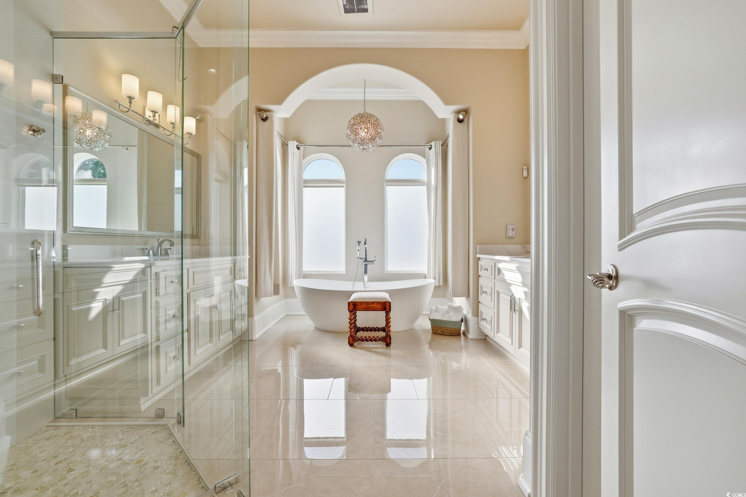 345 Posada Drive Myrtle Beach, SC 29572 - Photo 11 of 39 Primary bath featuring vanity, a freestanding tub, crown molding, a shower, and a chandelier