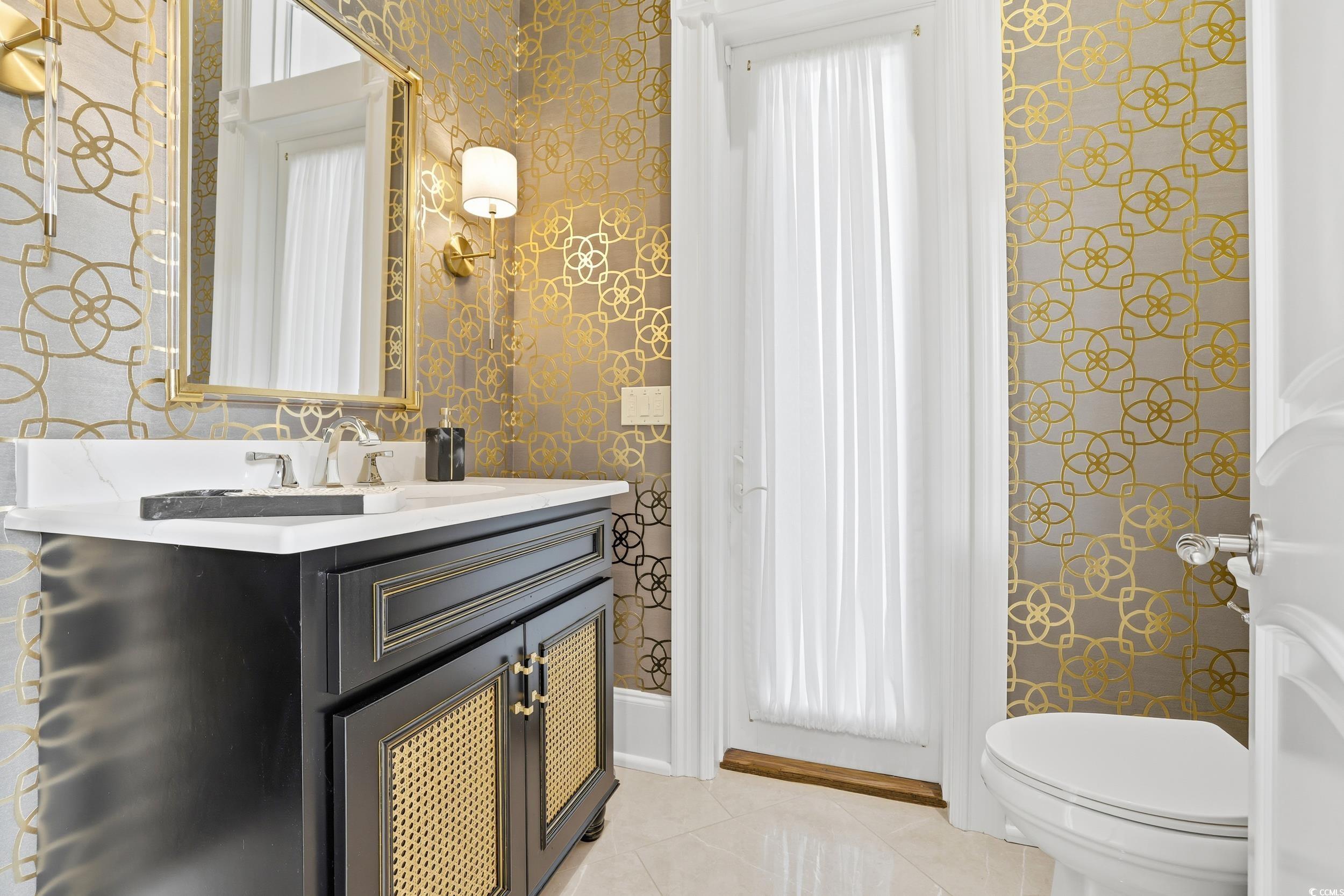 345 Posada Drive Myrtle Beach, SC 29572 - Photo 21 of 39 Powder Room with vanity, wallpapered walls, and light tile patterned floors that has door to the patio/pool.
