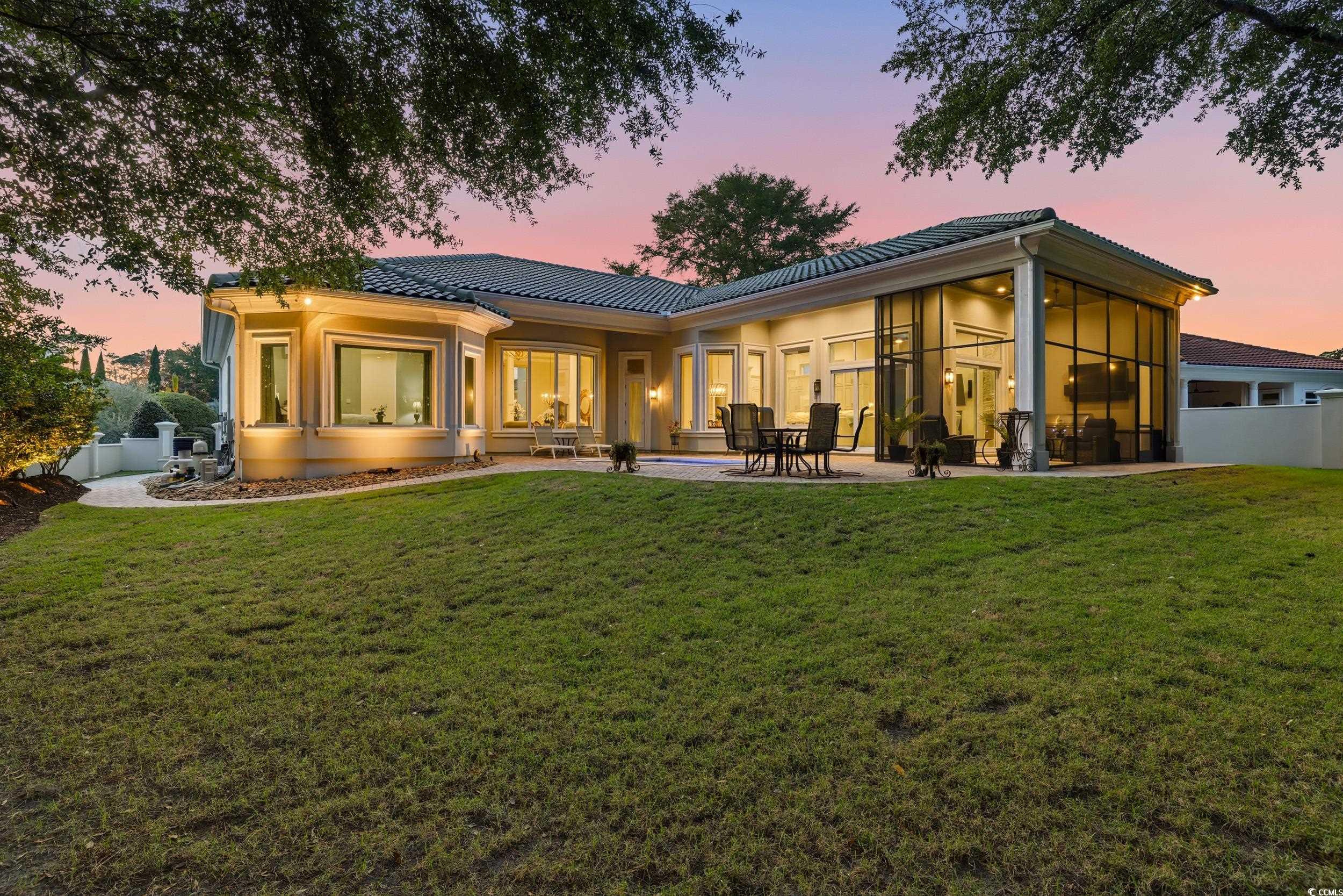 345 Posada Drive Myrtle Beach, SC 29572 - Photo 33 of 39 Back of property at dusk featuring a patio area, a tile roof, stucco siding, and a sunroom