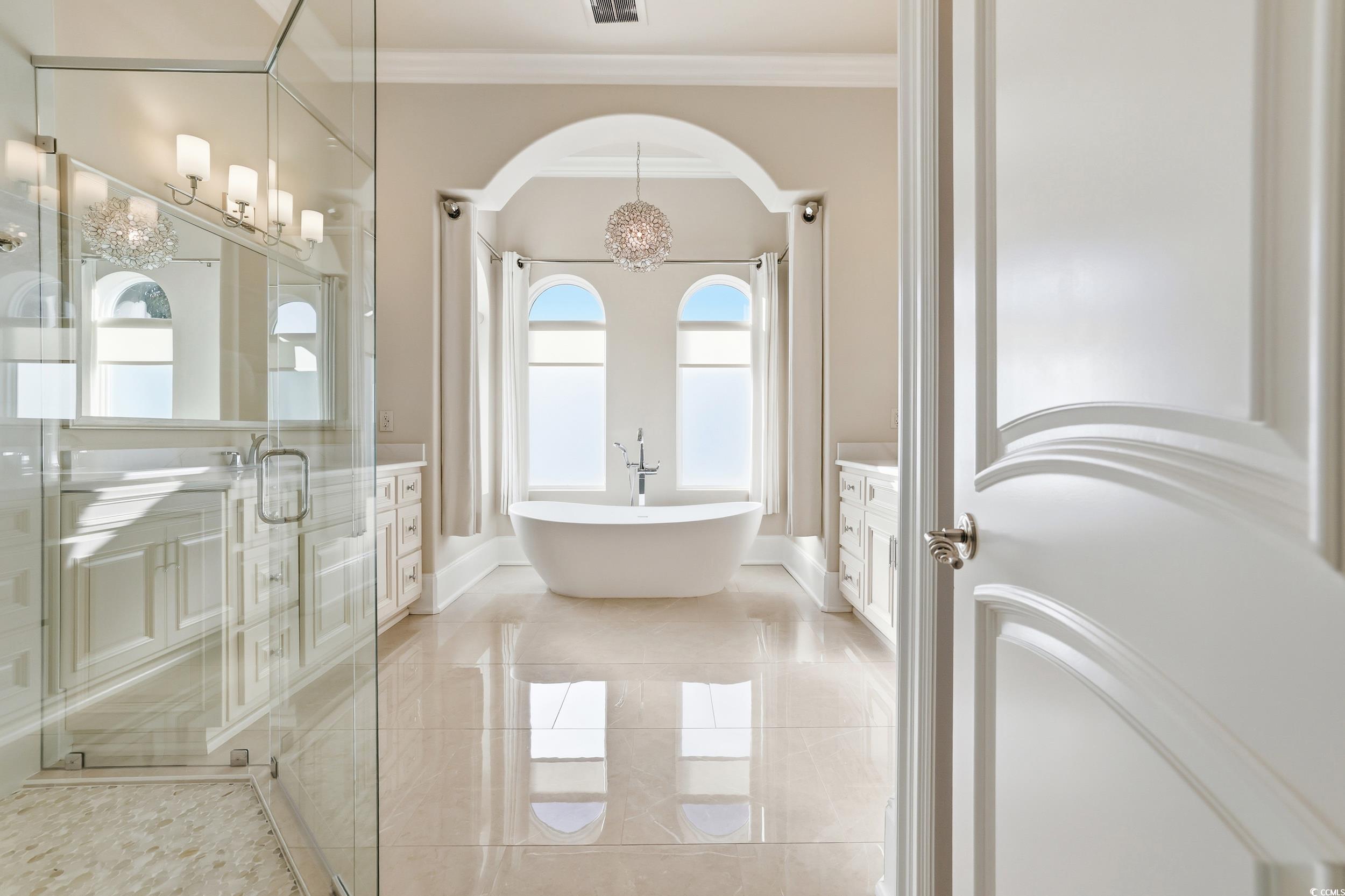 345 Posada Drive Myrtle Beach, SC 29572 - Photo 10 of 40 Primary bathroom with vanity, ornamental molding, a soaking tub, a chandelier, and a walk-in shower