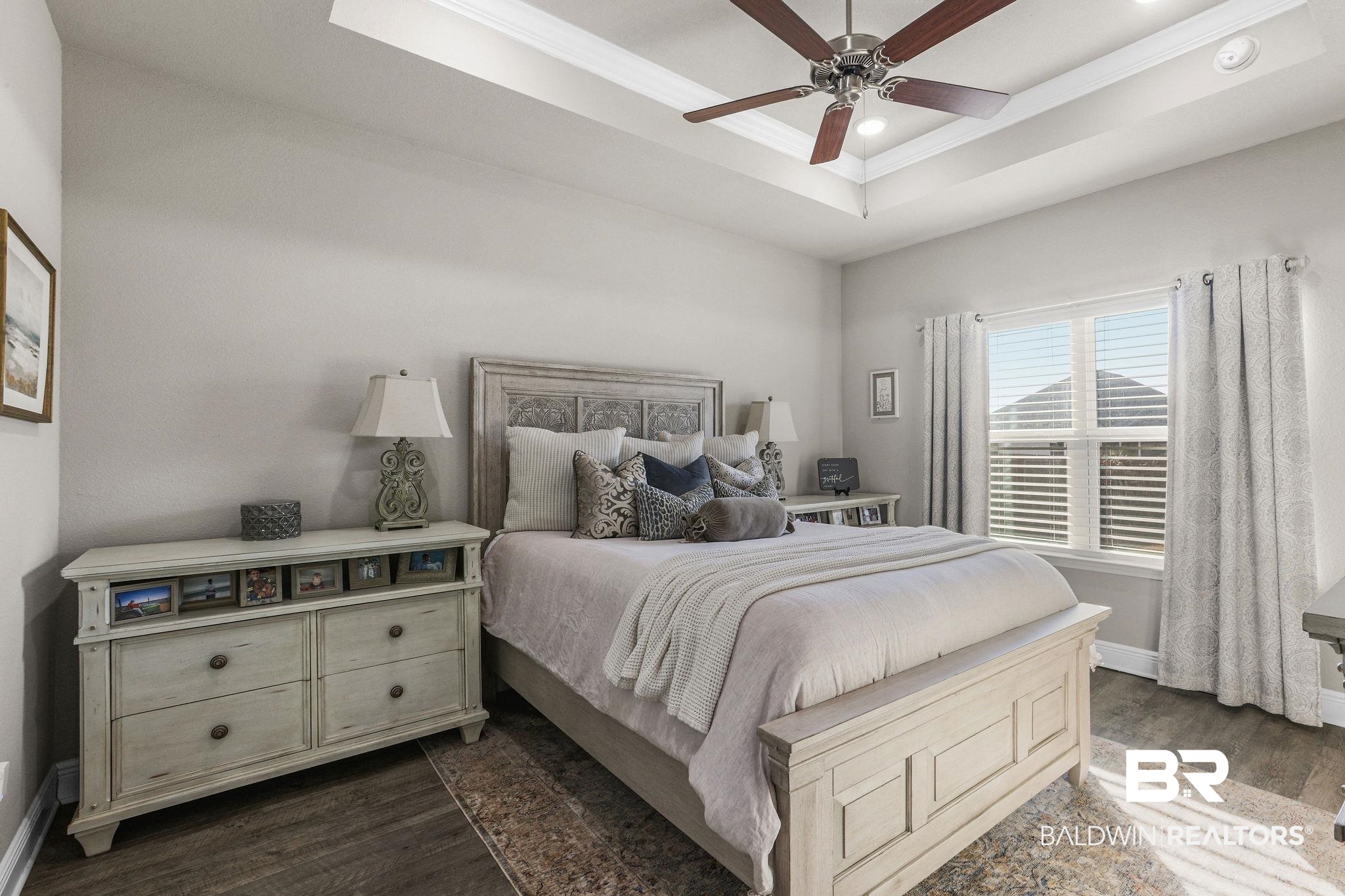 9056 Impala Drive Foley, AL 36535 - Photo 9 of 22 Bedroom featuring dark wood-type flooring, ceiling fan, a tray ceiling, and crown molding
