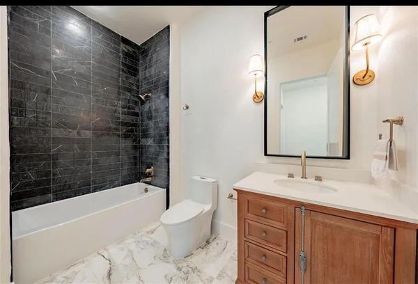 a bathroom with a bathtub shower sink vanity and toilet