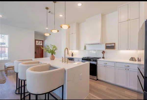 a kitchen with a stove a sink a kitchen island with chairs and wooden cabinets