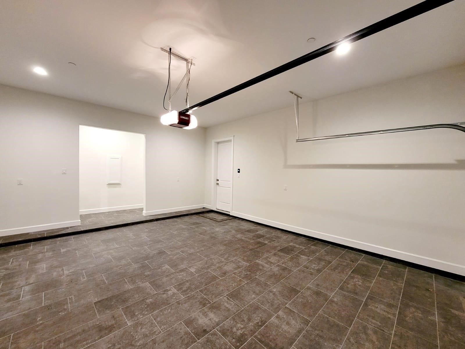 710 Delano Street, Unit A Houston, TX 77003 - Photo 28 of 32 The spacious, clean garage with tiled flooring, white walls, and ceiling lighting. It features a standard garage door opener and an internal door leading into the home.