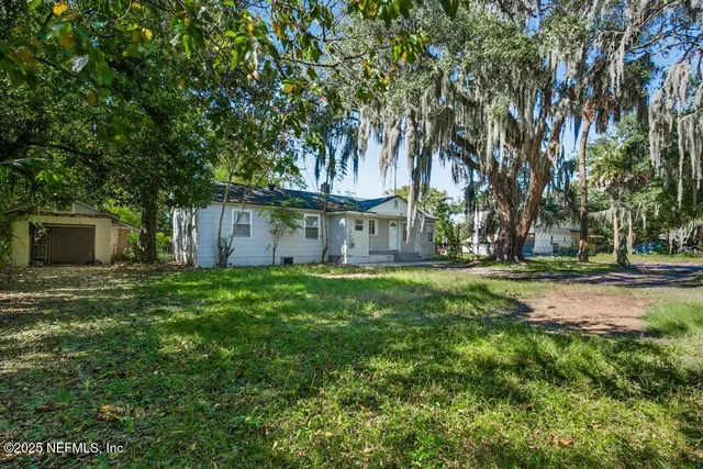 a view of a house with backyard and a tree