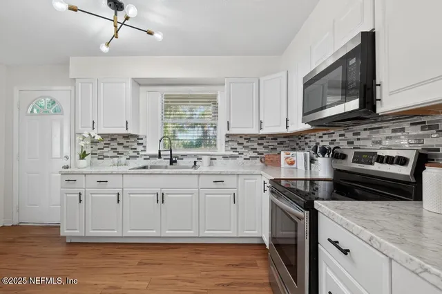 a kitchen with stainless steel appliances granite countertop a stove a sink and a microwave