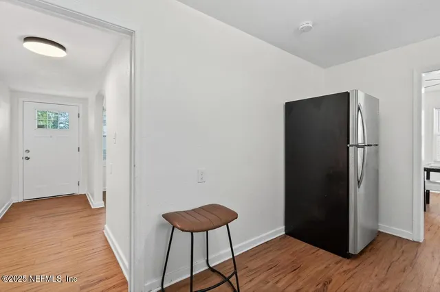 a view of a hallway with wooden floor and a bathroom