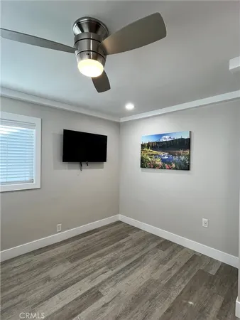 an empty room with wooden floor ceiling fan and window