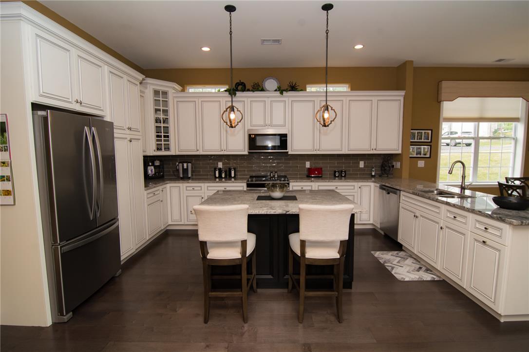 4097 Rutz Lane Allentown, PA 18104 - Photo 7 of 59 Rich hardwood floors anchor this kitchen designed with classic white cabinetry and a stone-topped island.