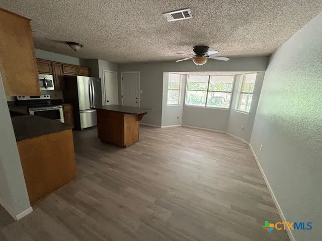 wooden floor in kitchen and an empty room with a window