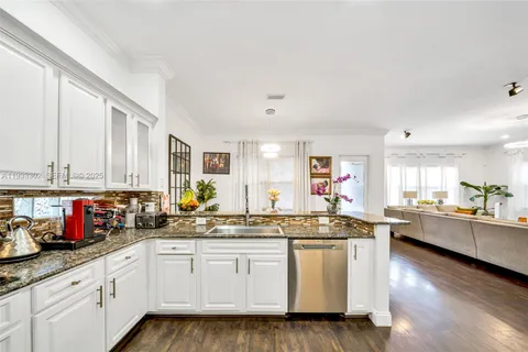 a large white kitchen with stainless steel appliances granite countertop a stove a sink dishwasher and a refrigerator