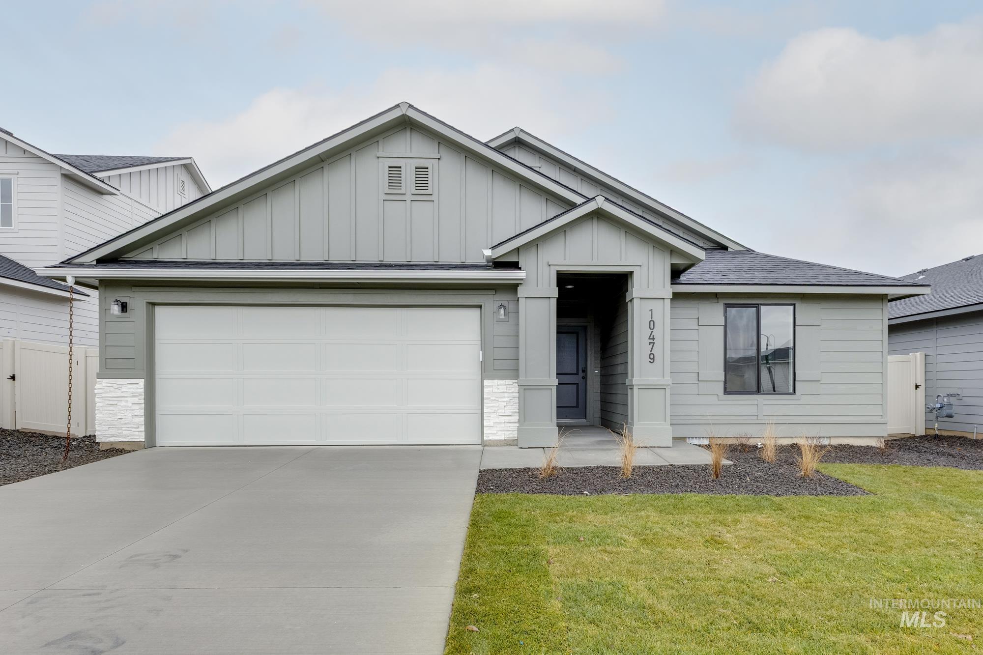 View of front facade with board and batten siding, stone siding, an attached garage, concrete driveway, and roof with shingles
