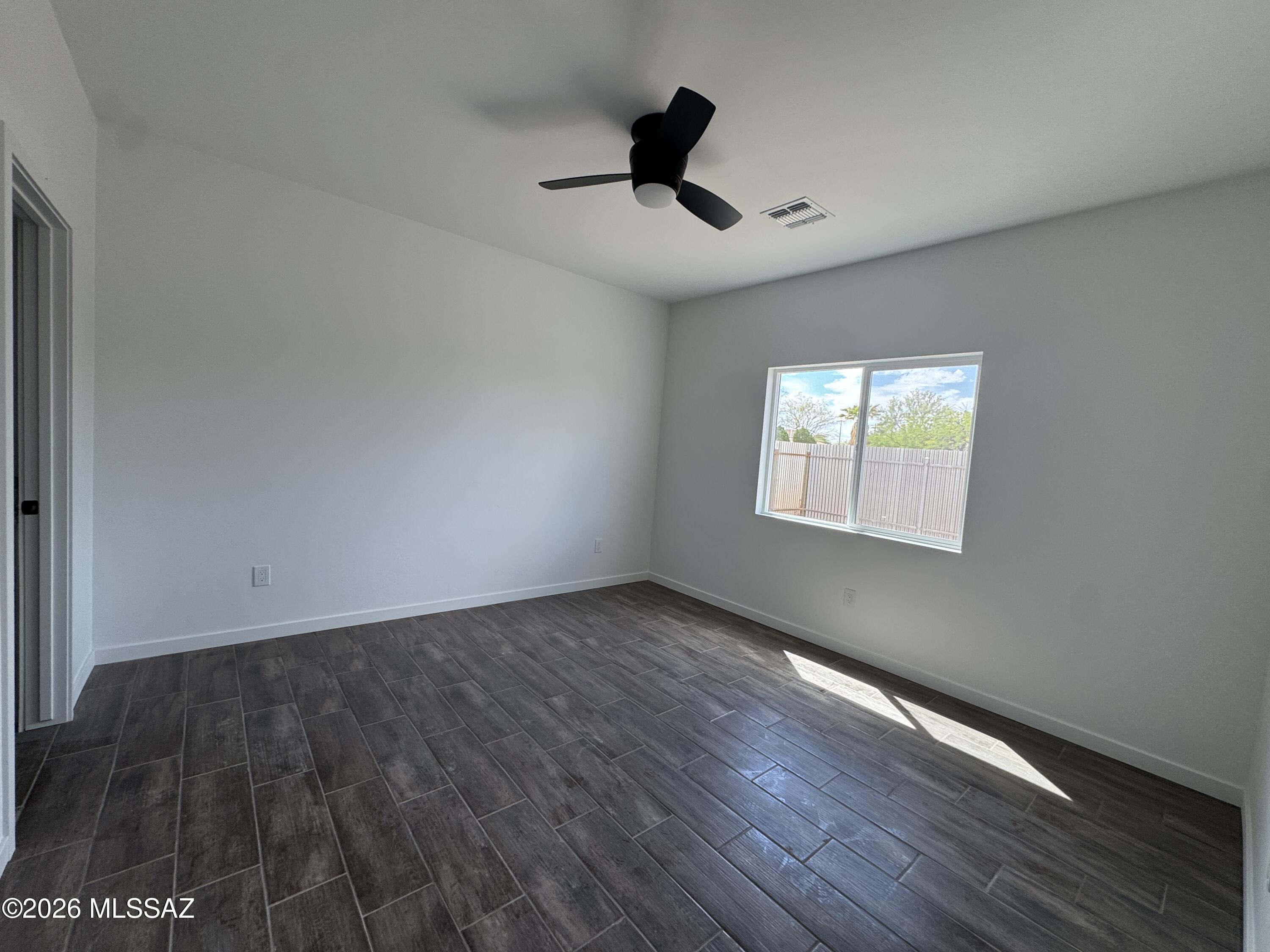 2122 North Ralph Avenue, Unit 1 Tucson, AZ 85712 - Photo 7 of 10 a view of an empty room with wooden floor and a window