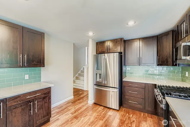 a kitchen with granite countertop a refrigerator and a stove top oven