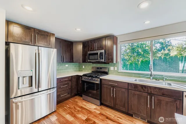 a kitchen with granite countertop stainless steel appliances a refrigerator cabinets and a sink