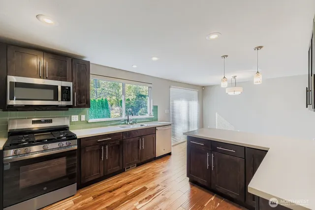 a kitchen with stainless steel appliances granite countertop a stove a sink and a microwave